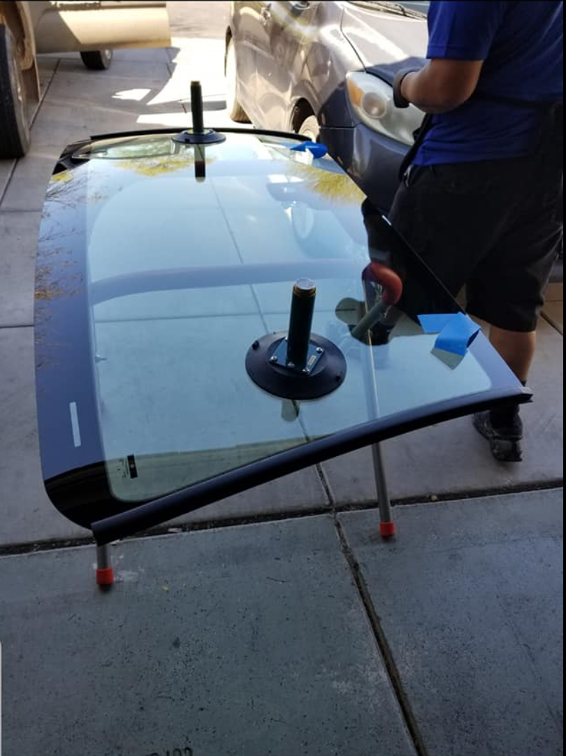 A new windshield resting on suction stands, ready to be set.